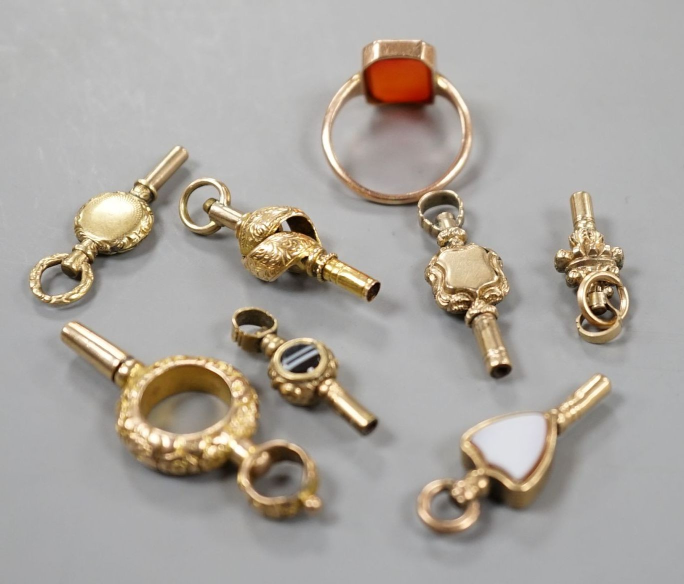 An early 20th century 9ct and carnelian set ring, size K/L, gross 2.7 grams and seven assorted watch keys including three set with chalcedony.